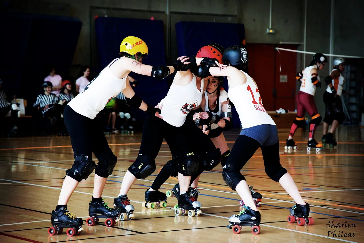 Un groupe de joueuses de roller derby en action sur une piste en salle.