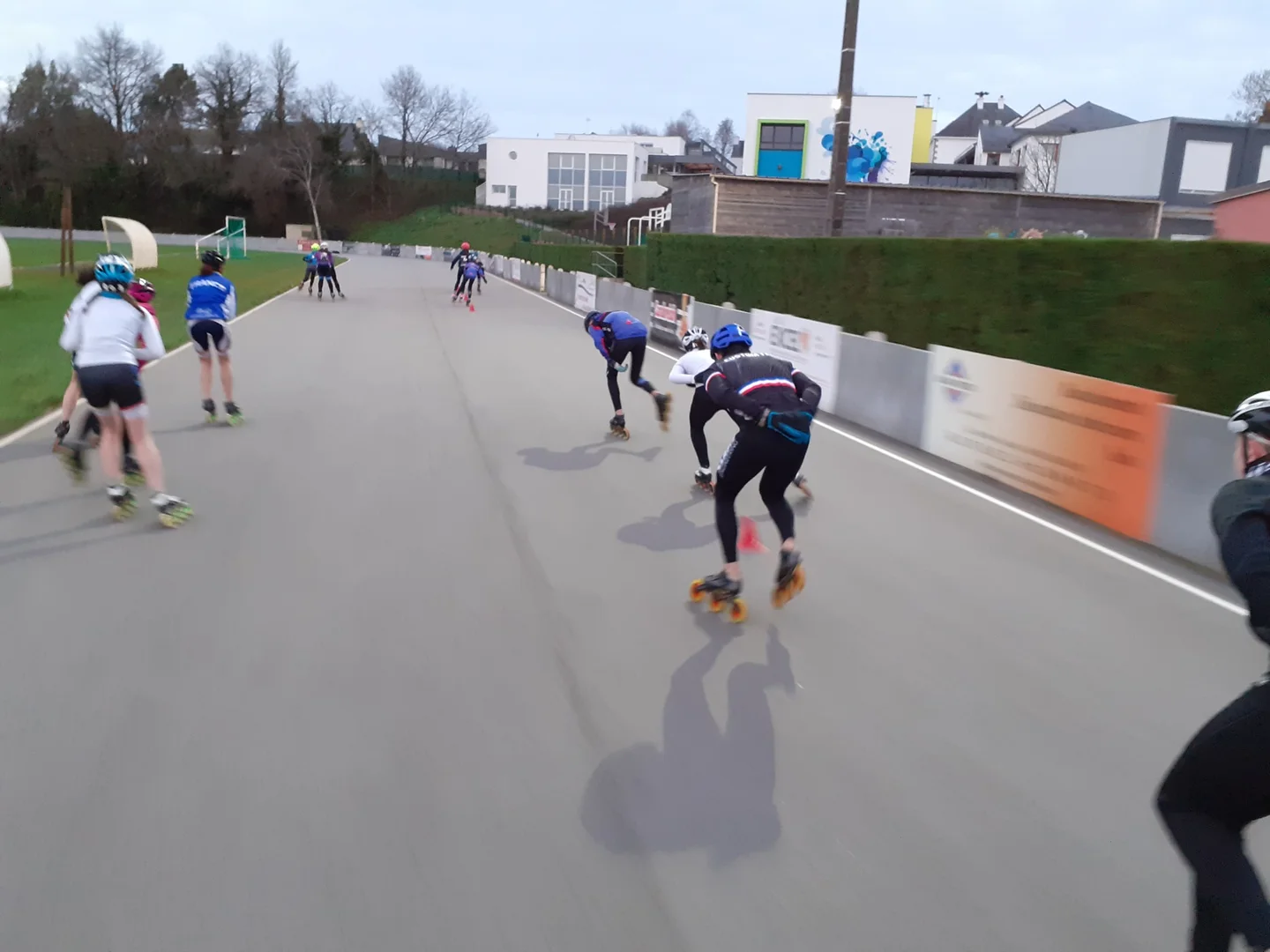 Des patineurs en roller en ligne, vus de dos, s’entraînent sur une piste extérieure.
